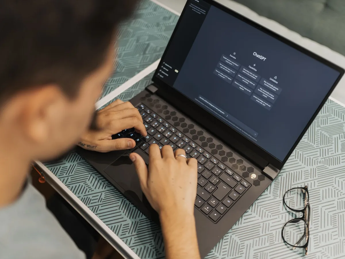 Un artisan dans son atelier consulte un logiciel de gestion sur un ordinateur portable posé près de son établi.