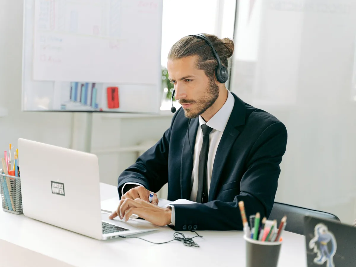 Un dirigeant de petite entreprise travaille sur un ordinateur portable avec un agent IA en arrière-plan sur l'écran