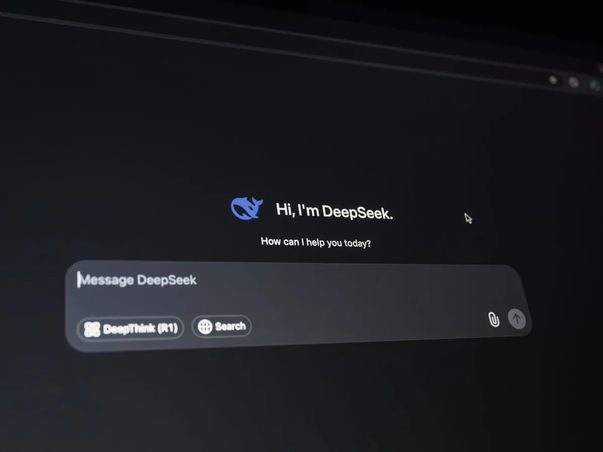 Un dirigeant de petite entreprise travaille sur son ordinateur portable, un assistant logiciel analyse des documents et des e-mails à l'écran