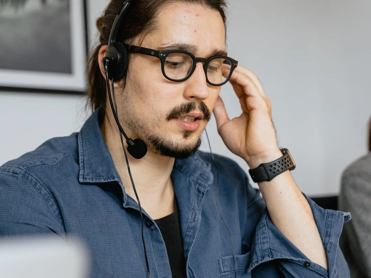 Un dirigeant de petite entreprise utilise un assistant intelligent sur son ordinateur portable, son téléphone posé sur le bureau à côté des devis en cours.