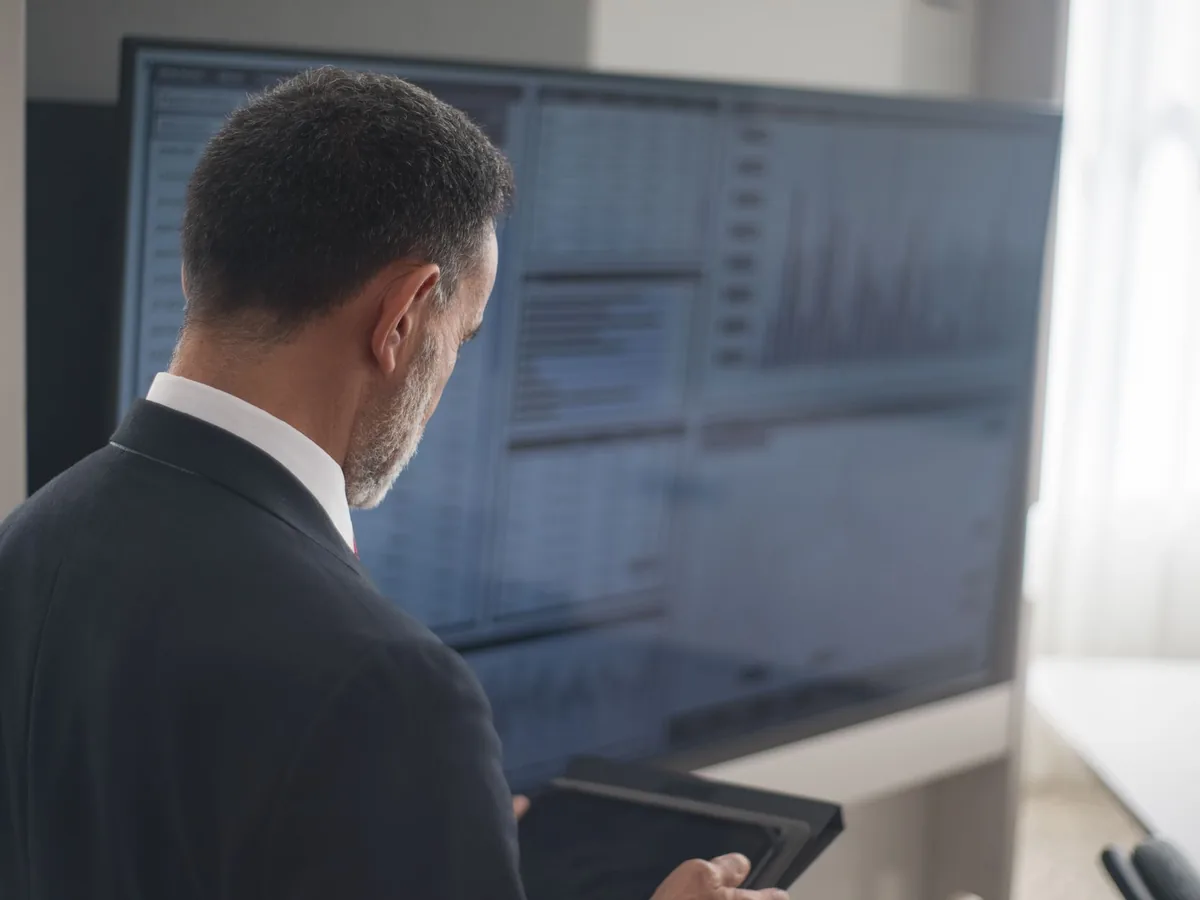 Un chef d'entreprise examine attentivement sur son ordinateur portable les données traitées par un agent intelligence artificielle dans son atelier.