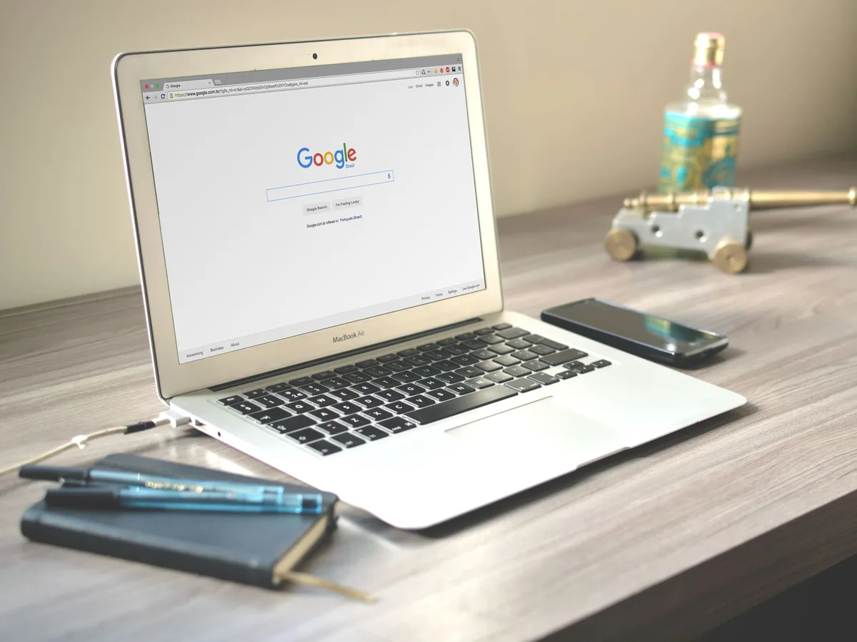 Un artisan dans son atelier consulte la fiche Google de son entreprise sur son smartphone, l'écran affichant des avis clients étoilés.