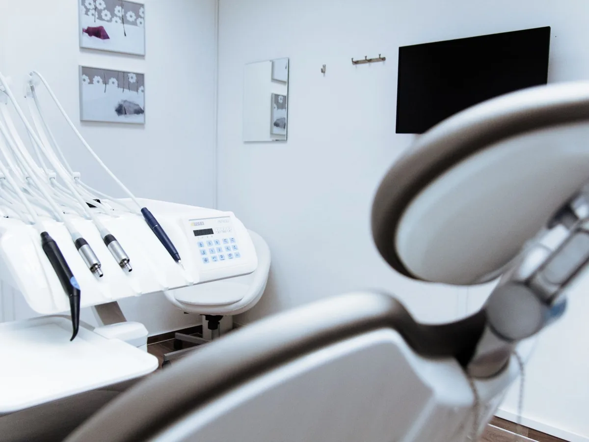 Un dentiste dans son cabinet consulte un site médical sur son smartphone entre deux patients.