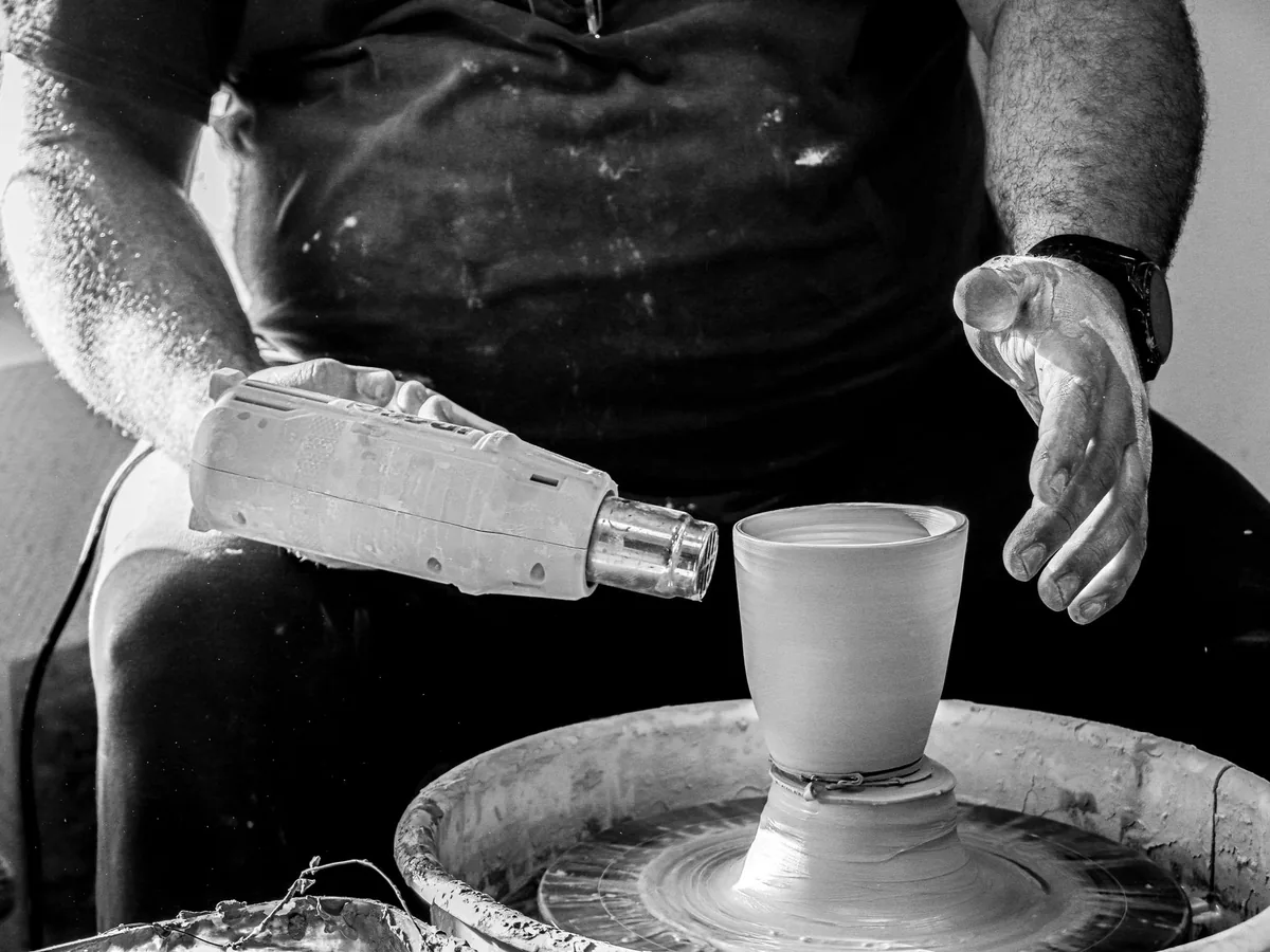 Artisan dans son atelier de Montbrison consultant son site web sur un smartphone, photos de chantier affichées à l'écran.