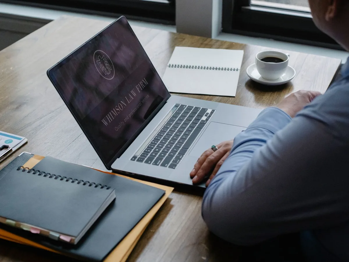 Un avocat en robe consulte le site web de son cabinet sur un ordinateur portable dans son bureau.