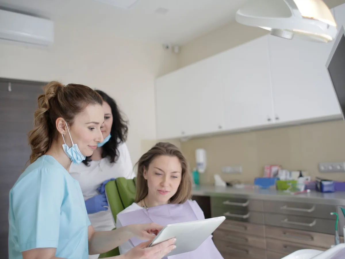 Un patient lisant un devis dentaire imprimé en présence d'un chirurgien-dentiste dans son cabinet