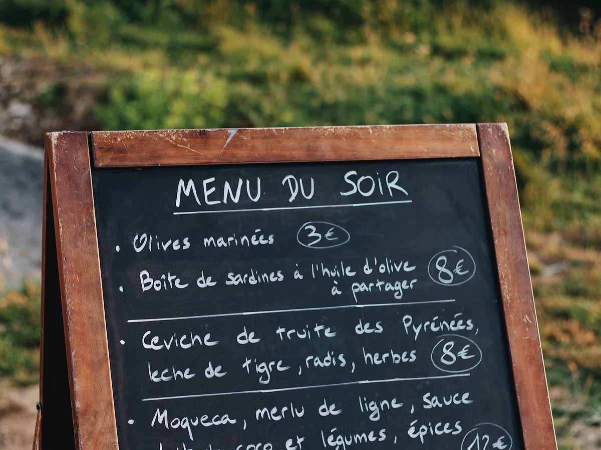 Un restaurateur remplit un modèle de devis sur un ordinateur portable posé sur le comptoir de son restaurant.