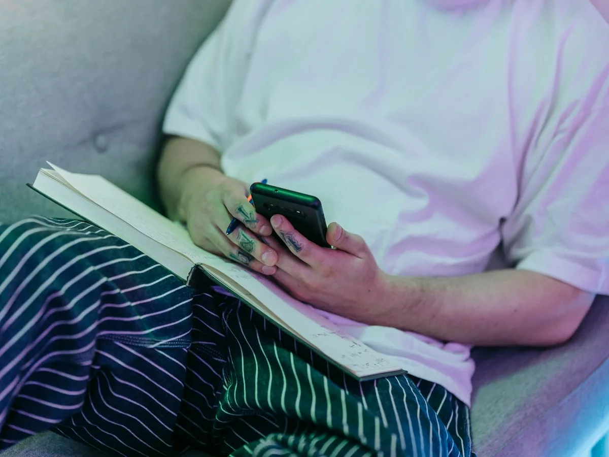 Un client assis qui consulte son téléphone, un carnet ouvert sur les genoux