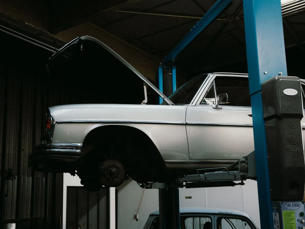 Un mécanicien en bleu de travail consulte un devis dans un atelier de réparation automobile.